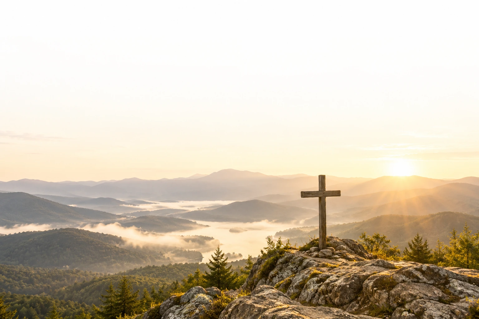 A wooden cross overlooking mountain ridges at sunrise